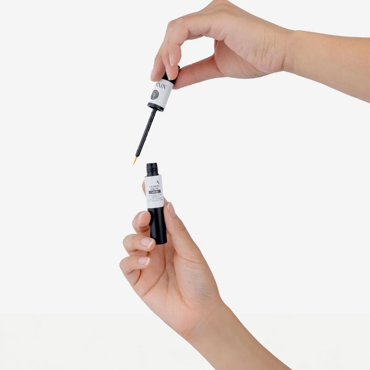 Sérum voluminizador de pestañas divain Care con aplicador en mano.