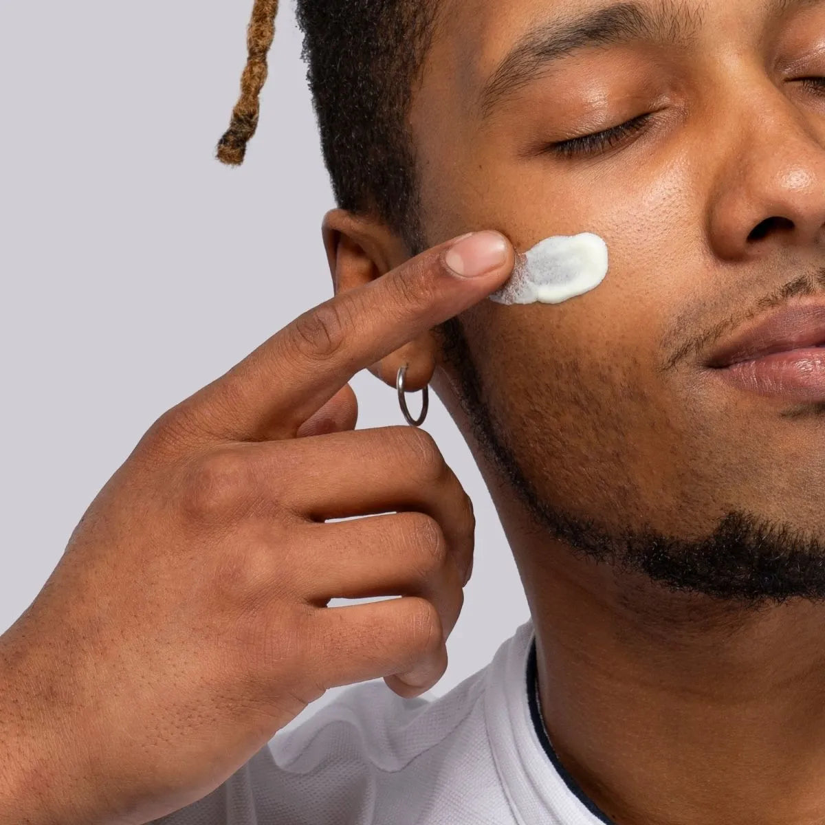 Aplicación de crema divain Care sobre la piel del rostro masculino.