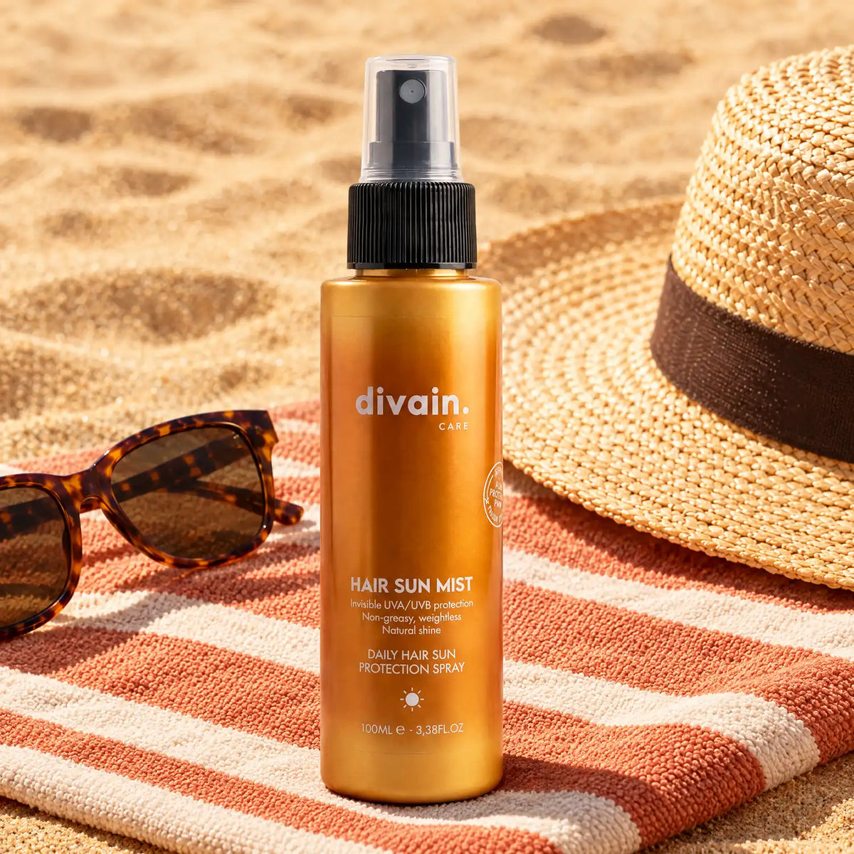 Hair Sun Mist sobre una toalla de playa con gafas de sol y sombrero