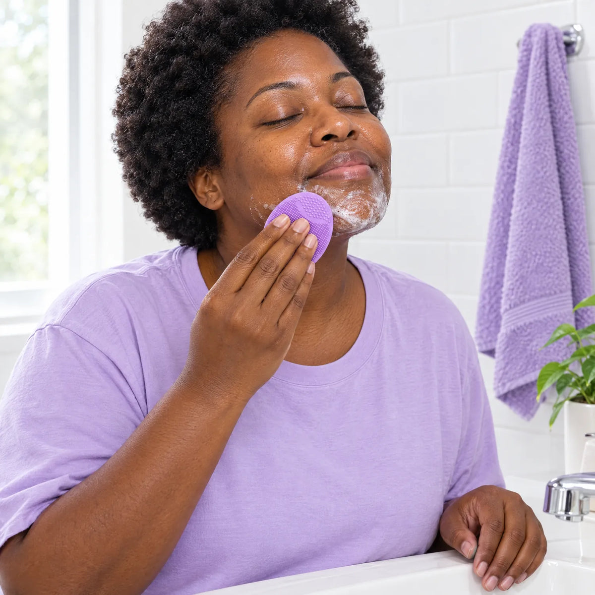 Mujer usando el cepillo facial de silicona en el lavabo