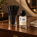 Tiras olfativas divain. en un vaso junto a un perfume divain.