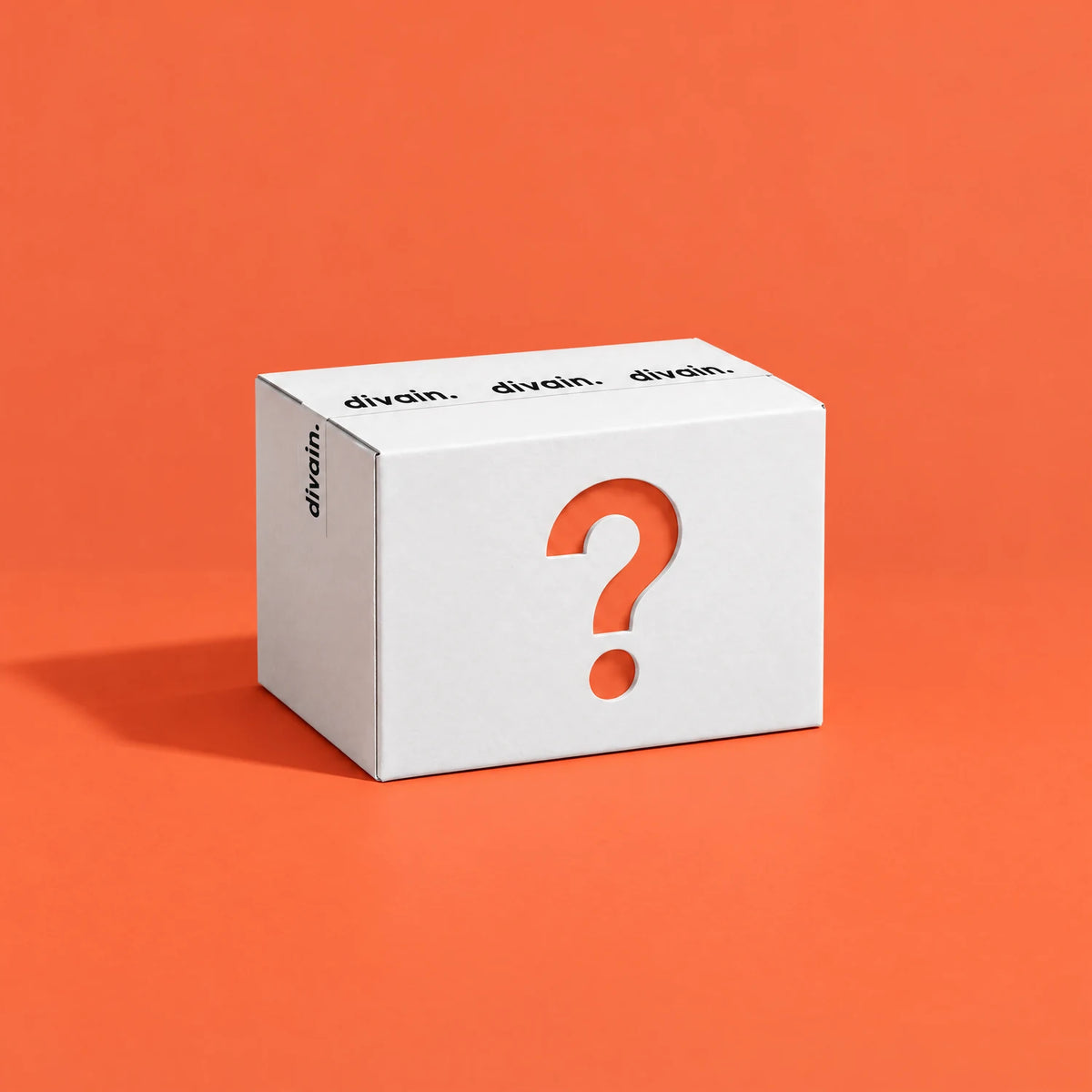Mystery Box de divain.: caja sorpresa blanca con interrogante naranja
