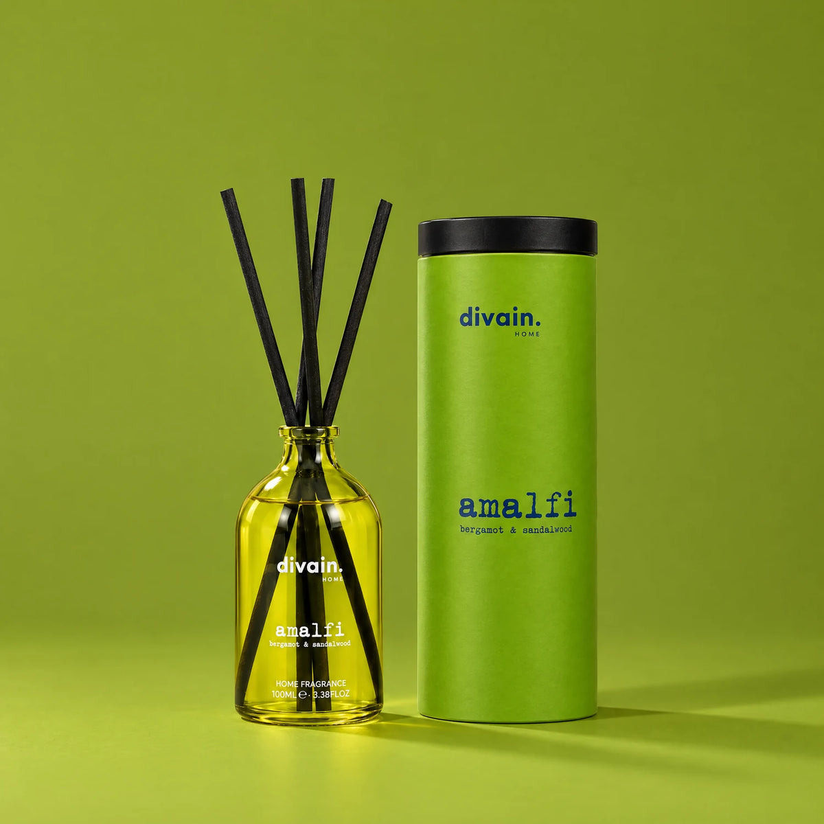 Ambientador mikado Amalfi de divain. con su tubo sobre fondo verde oliva