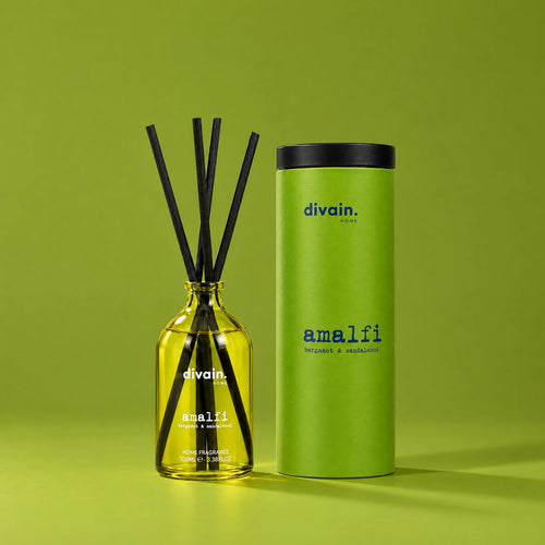 Ambientador mikado Amalfi de divain. con su tubo sobre fondo verde oliva