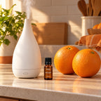 Aceite esencial de naranja dulce en la encimera junto a un difusor y naranjas