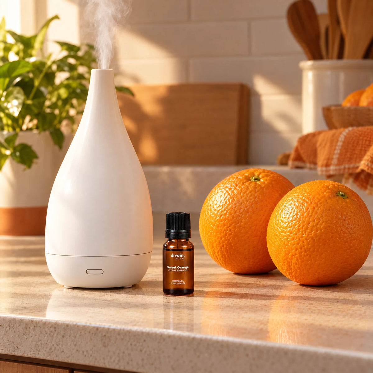 Aceite esencial de naranja dulce en la encimera junto a un difusor y naranjas