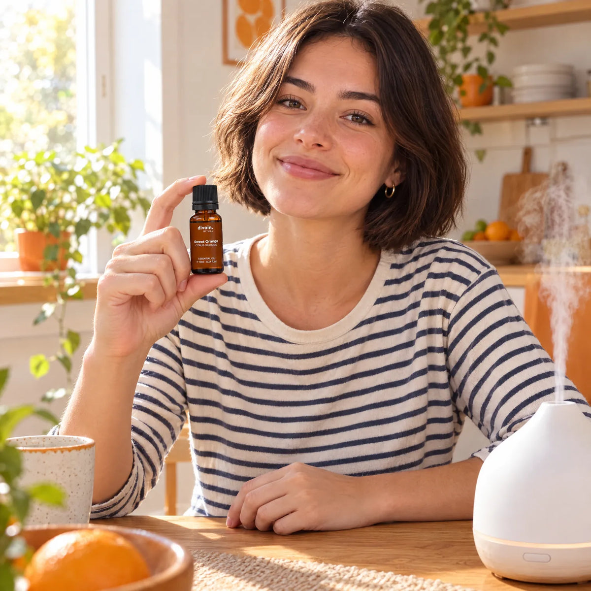 Mujer joven en su cocina con el aceite esencial de naranja dulce