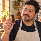 Hombre con delantal en la cocina con el aceite esencial de naranja dulce