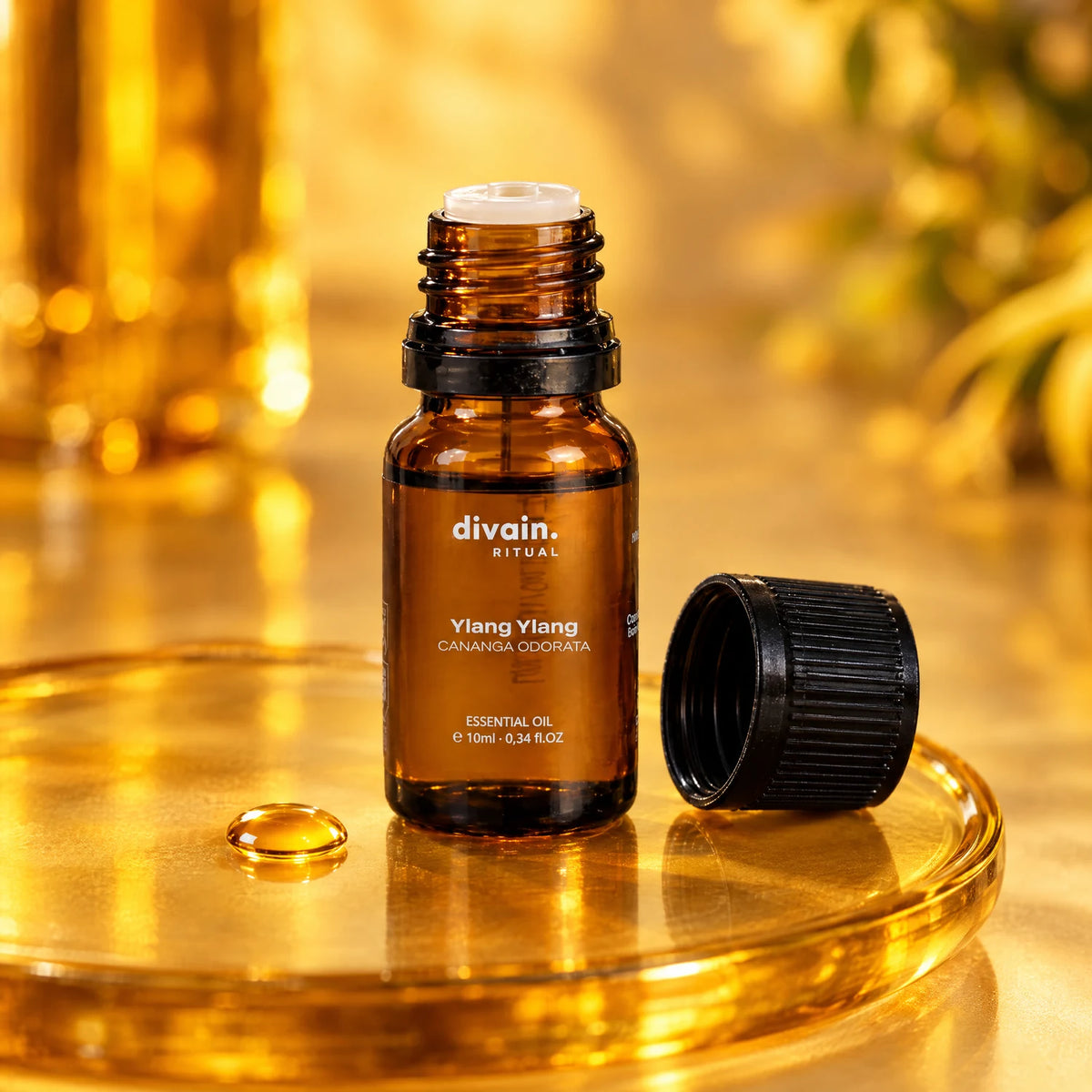 Frasco abierto con cuentagotas y una gota de aceite de ylang ylang