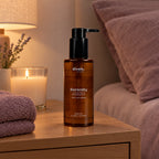 Serenity Body Oil en la mesilla junto a una vela y una toalla
