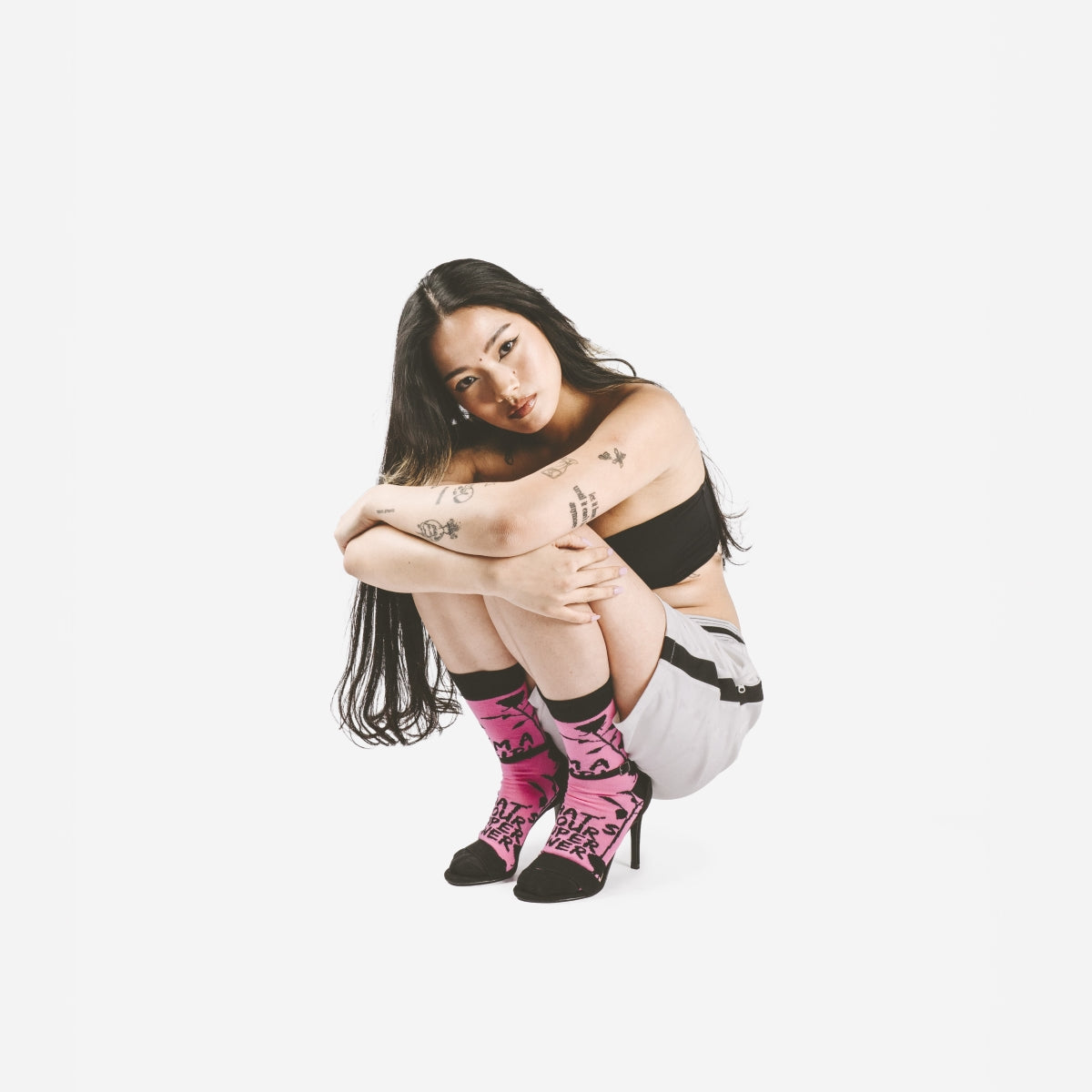 Modelo en cuclillas con los tacones negros de aguja y los calcetines puestos