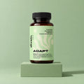 ADAPT divain. ZEN, complemento de magnesio, ashwagandha y triptófano sobre fondo verde salvia