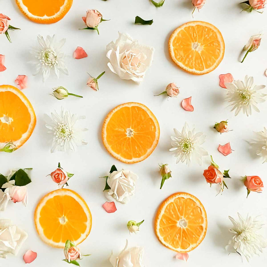 Notas olfativas cítricas y florales con rodajas de naranja, rosas blancas y flores rosadas