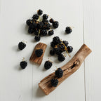 Madera y grosellas negras representando las notas olfativas del perfume.