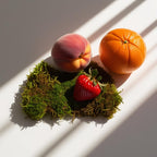 Melocotón, mandarina, fresa y musgo representando las notas olfativas del perfume.